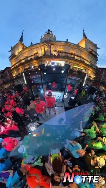 Grupo con camisetas rosas de Nostra Notte ante la plaza abarrotada durante la gira